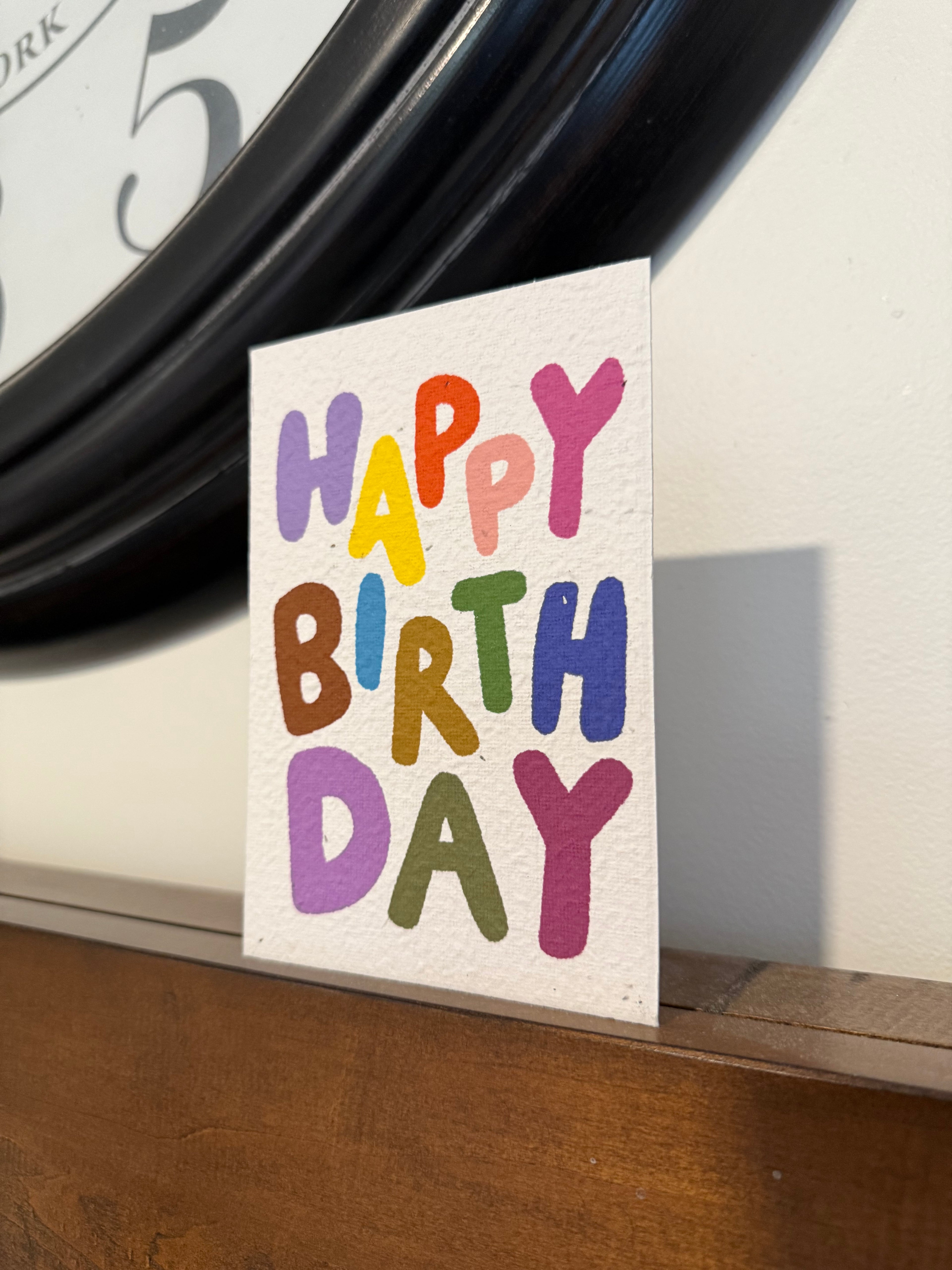A happy birthday plantable card with bright letters on it 